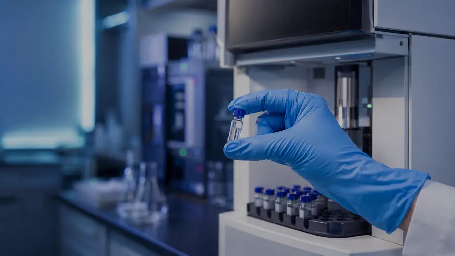 A gloved hand holding a laboratory sample vial